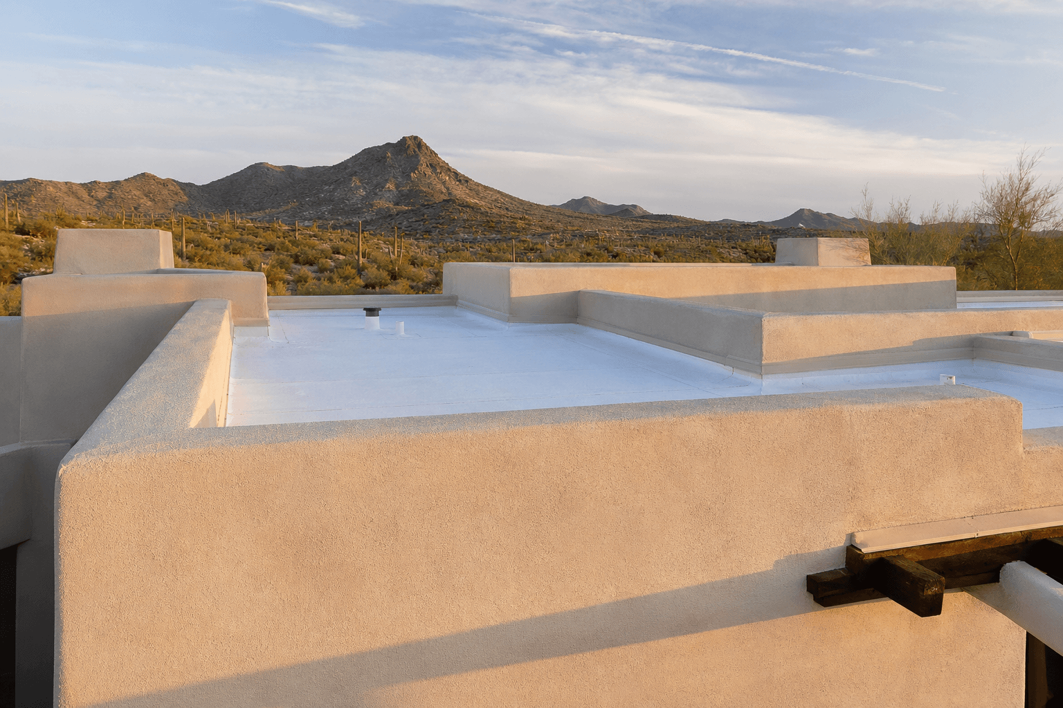 Low-slope stucco parapet walls with flat foam roof surface.